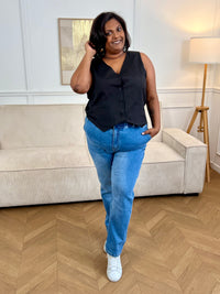 Adoptez ce gilet court de tailleur grande taille femme, élégant et structuré. Sans manches, il se distingue par son col V flatteur et ses boutons sur toute la longueur. Ses deux poches factices à l’avant apportent une touche chic supplémentaire. En noir, il complète parfaitement un look habillé ou moderne.