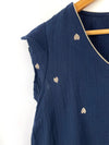 La blouse bleue Sacha en gaze de coton est une tenue incontournable pour votre garde-robe! Avec ses motifs de coeurs dorés et ses volants, elle ajoutera une touche de charme à votre look. 