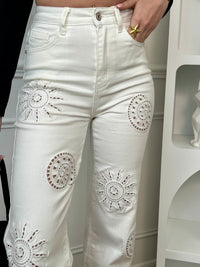 Jean blanc femme taille haute, idéal pour un look tendance et lumineux. Avec sa coupe droite et ses deux poches à l’avant et à l’arrière, il allie confort et style au quotidien. Ses détails en broderie ajourée à l’avant, en forme de coquillage et de soleil, apportent une touche originale et estivale. Doté de passants pour ceinture, ce jean blanc est parfait pour composer des tenues chic et décontractées.
