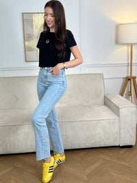 Jean bleu femme coupe straight intemporelle, agrémenté de motifs ananas brodés en jaune et vert pour une touche de couleur ludique. Fermeture à zip et bouton, quatre poches pratiques. Confectionné en coton, ce jean allie confort et style décontracté, parfait pour un look casual chic au quotidien.