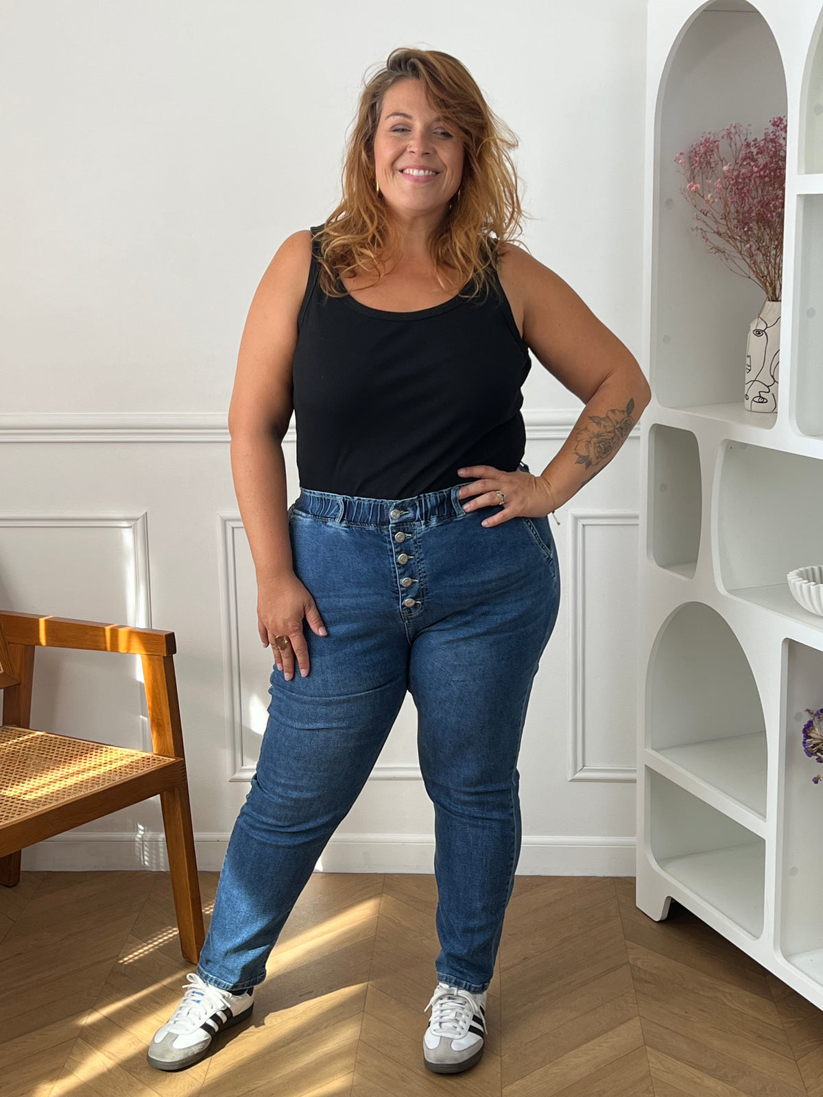 Jean bleu Felicie porté de face, montrant la taille froncée, la fermeture à boutons et les jambes fuselées, avec des baskets.
