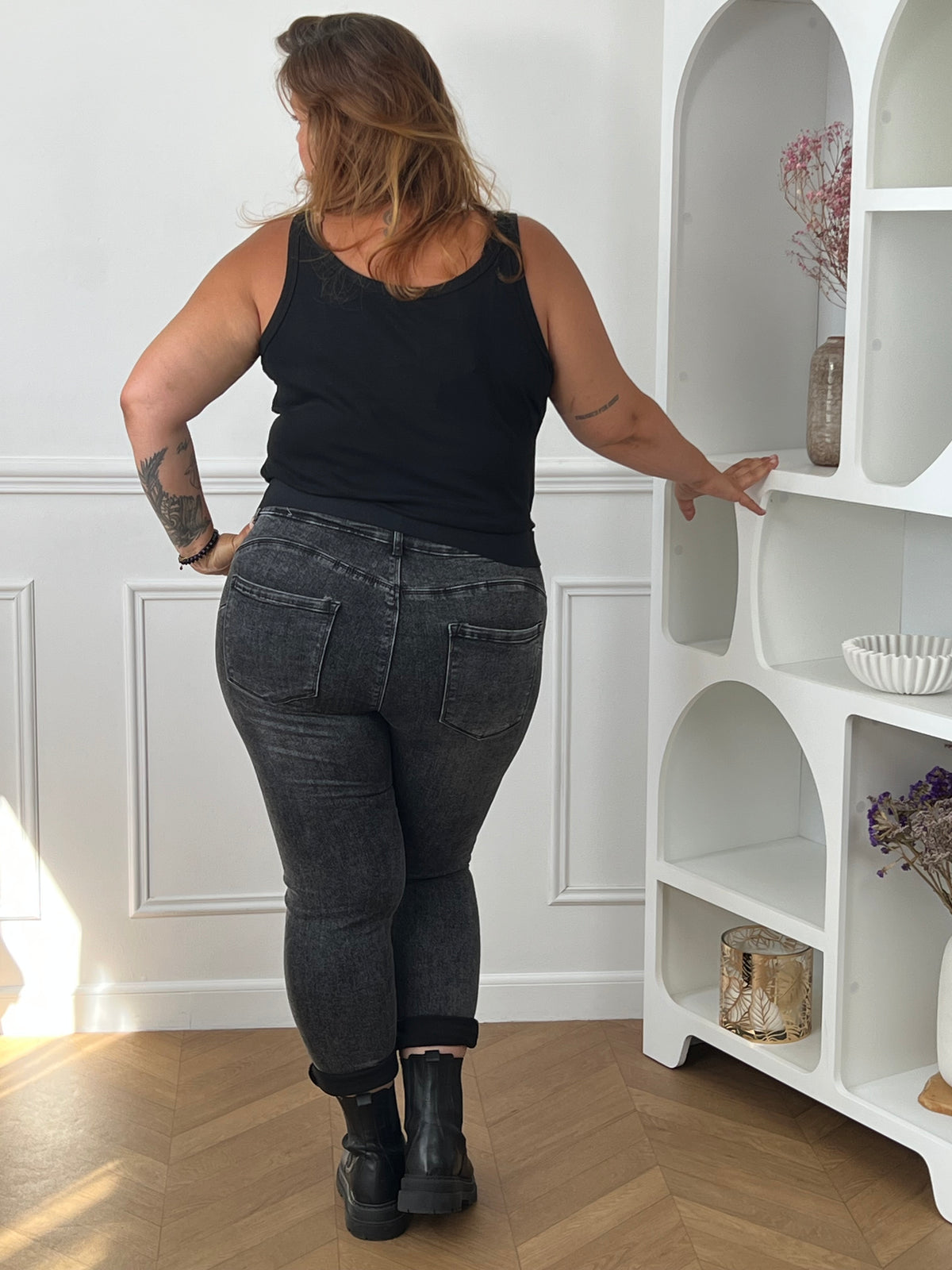 Jean gris anthracite taille haute grande taille - vue de dos avec débardeur noir mettant en valeur la coupe ajustée aux hanches et le bas retroussé