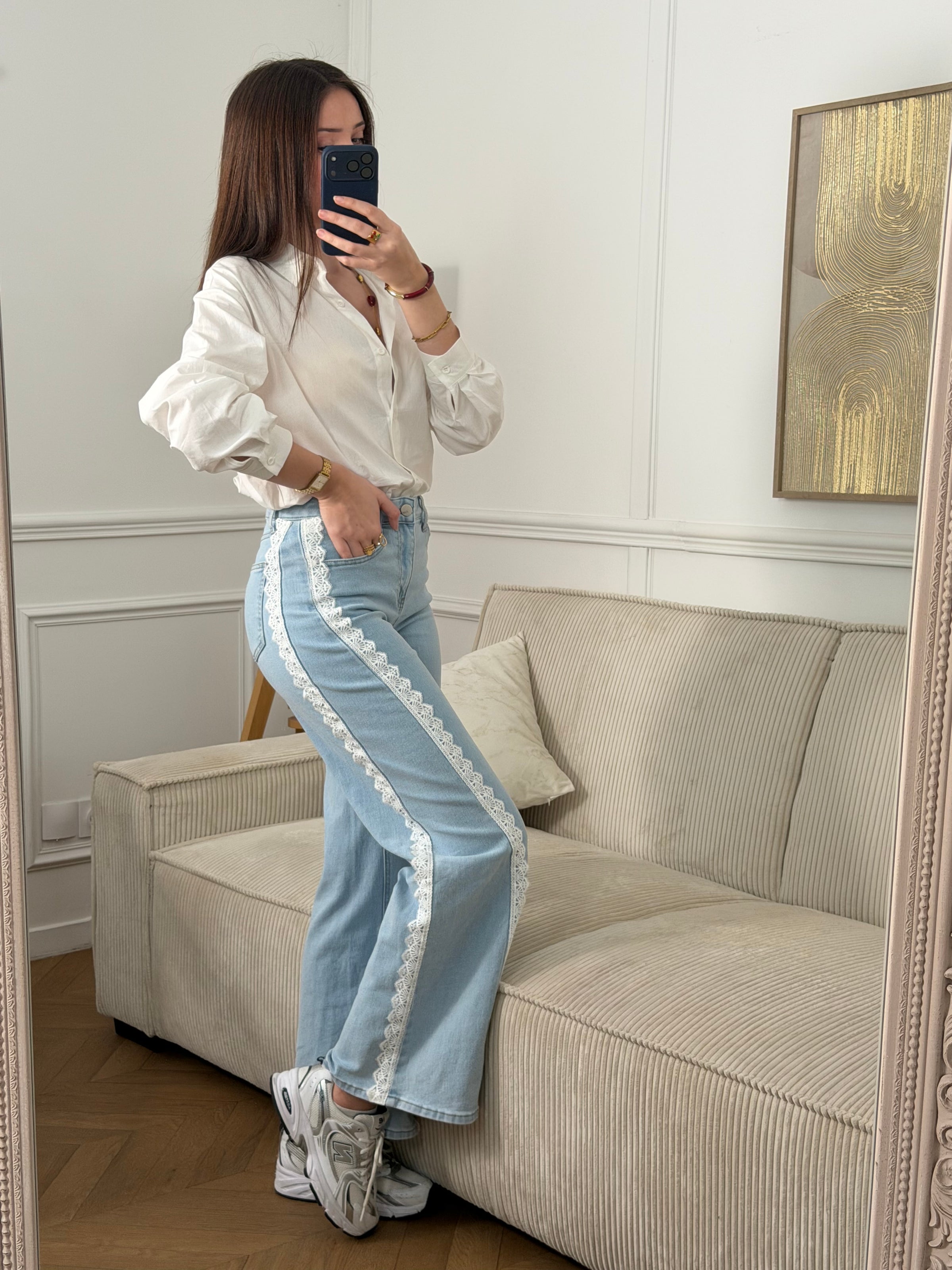 Jean bleu femme coupe large et intemporelle. Fermeture à zip et bouton pour un maintien sûr. Quatre poches pratiques pour ranger vos essentiels. Détail broderie élégant qui court sur toute la longueur, apportant une touche de caractère à votre garde-robe. Disponible en bleu classique et écru subtil.