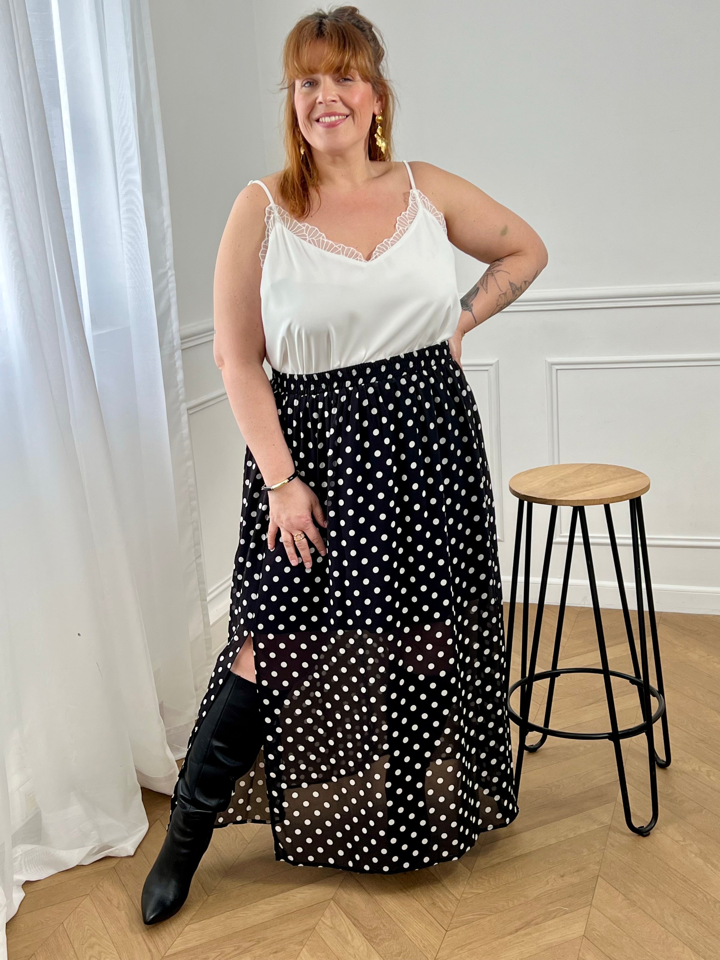 Adoptez cette jupe longue à pois grande taille, à la fois chic et confortable. Sa taille élastiquée s’ajuste facilement à votre silhouette. Ses motifs noir et écru apportent une touche intemporelle, tandis que sa fente sur le côté droit et sa doublure jusqu’aux genoux offrent fluidité et aisance au quotidien.