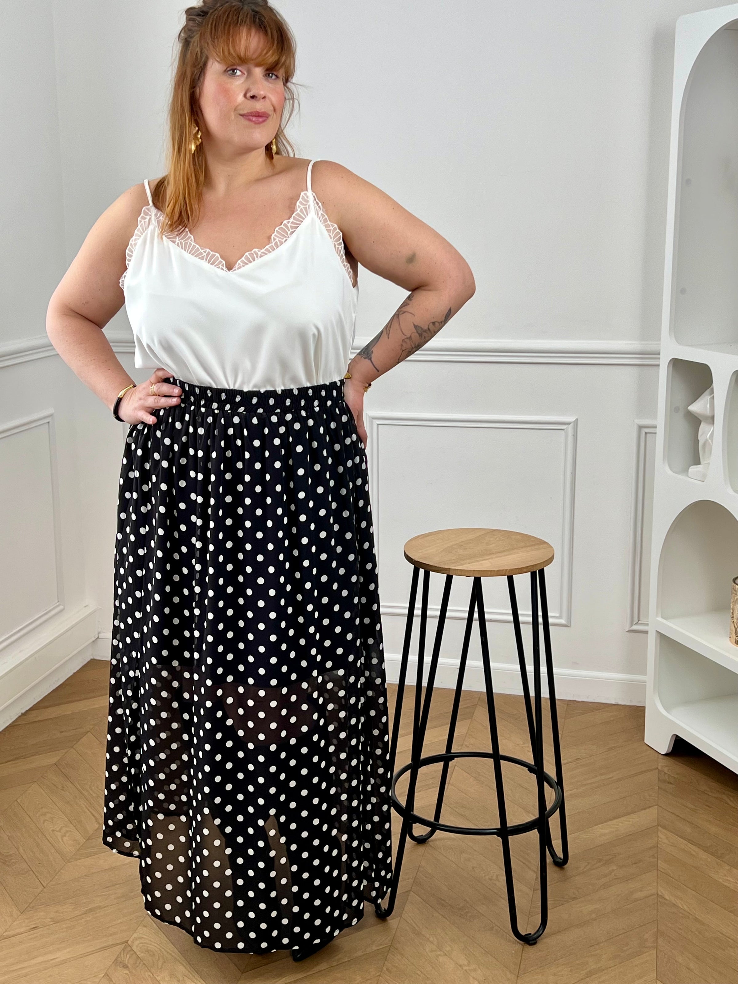 Adoptez cette jupe longue à pois grande taille, à la fois chic et confortable. Sa taille élastiquée s’ajuste facilement à votre silhouette. Ses motifs noir et écru apportent une touche intemporelle, tandis que sa fente sur le côté droit et sa doublure jusqu’aux genoux offrent fluidité et aisance au quotidien.