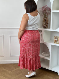 Jupe longue rouge grande taille femme, au style portefeuille, idéale pour une allure féminine et élégante. Dotée d’une taille élastique, elle offre un confort optimal au quotidien. Son volant apporte du mouvement, tandis que son motif floral rehaussé de fil lurex doré ajoute une touche lumineuse et raffinée. Parfaite pour sublimer vos tenues avec style.
