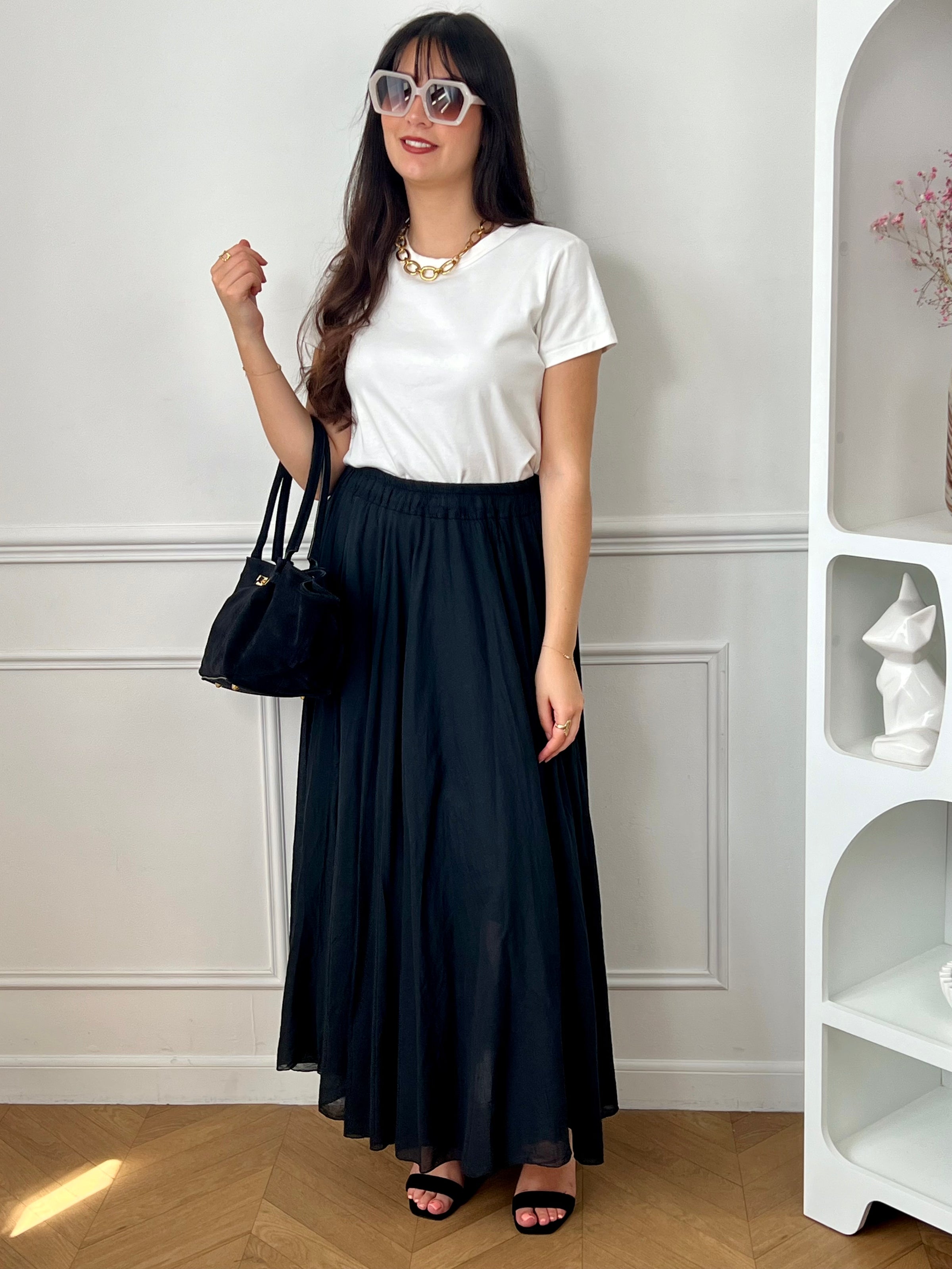 Jupe noire longue femme, légère et agréable à porter, parfaite pour un look élégant au quotidien. Dotée d’une taille élastique, elle assure un confort optimal et s’adapte facilement à la silhouette. Sa doublure jusqu’à mi-longueur garantit une bonne opacité, tandis que sa légère transparence apporte une touche féminine et raffinée. Confectionnée en 100% coton, cette jupe noire est un basique incontournable.