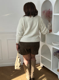 Jupe-short kaki Adele portée de dos, montrant la coupe du short, avec un gilet écru et des bottes beiges.