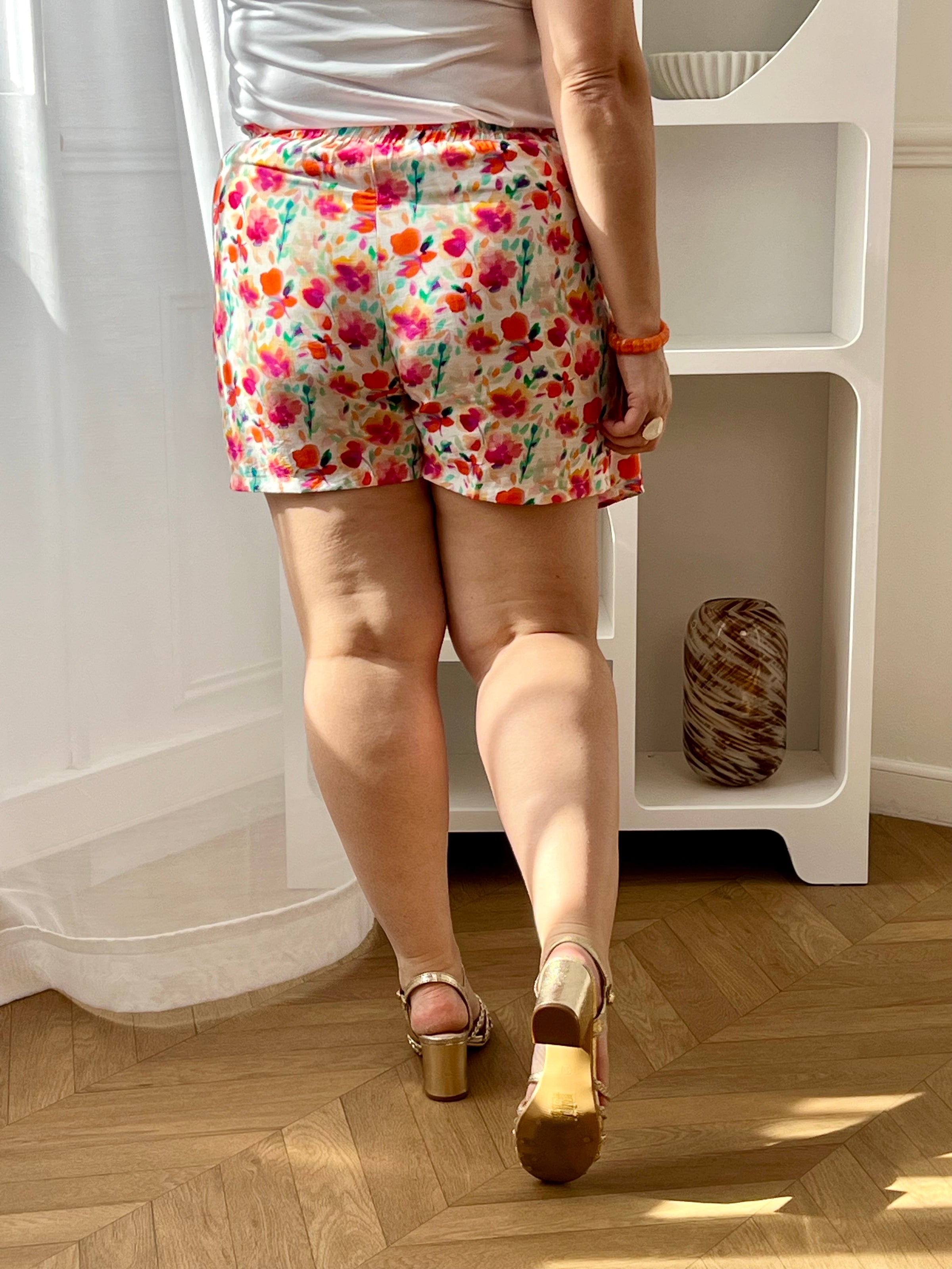 Craquez pour cette jupe-short portefeuille grande taille à motifs, féminine et pratique. Sa coupe portefeuille avec liens à nouer et son élastique à la taille assurent un ajustement confortable. Ses motifs floraux aux tons rose, orange, bleu, violet, vert, jaune et écru apportent une touche colorée et estivale à votre look.