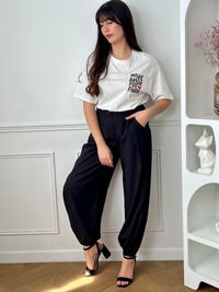Pantalon noir femme à coupe ballon, idéal pour un look moderne et confortable. Doté de plis sur le devant, d’une taille élastique et de chevilles resserrées, il offre une silhouette tendance. Ses deux poches latérales, sa fermeture par zip et bouton ainsi que ses passants pour ceinture allient praticité et style. Facile à associer, ce pantalon noir est un incontournable du dressing féminin.