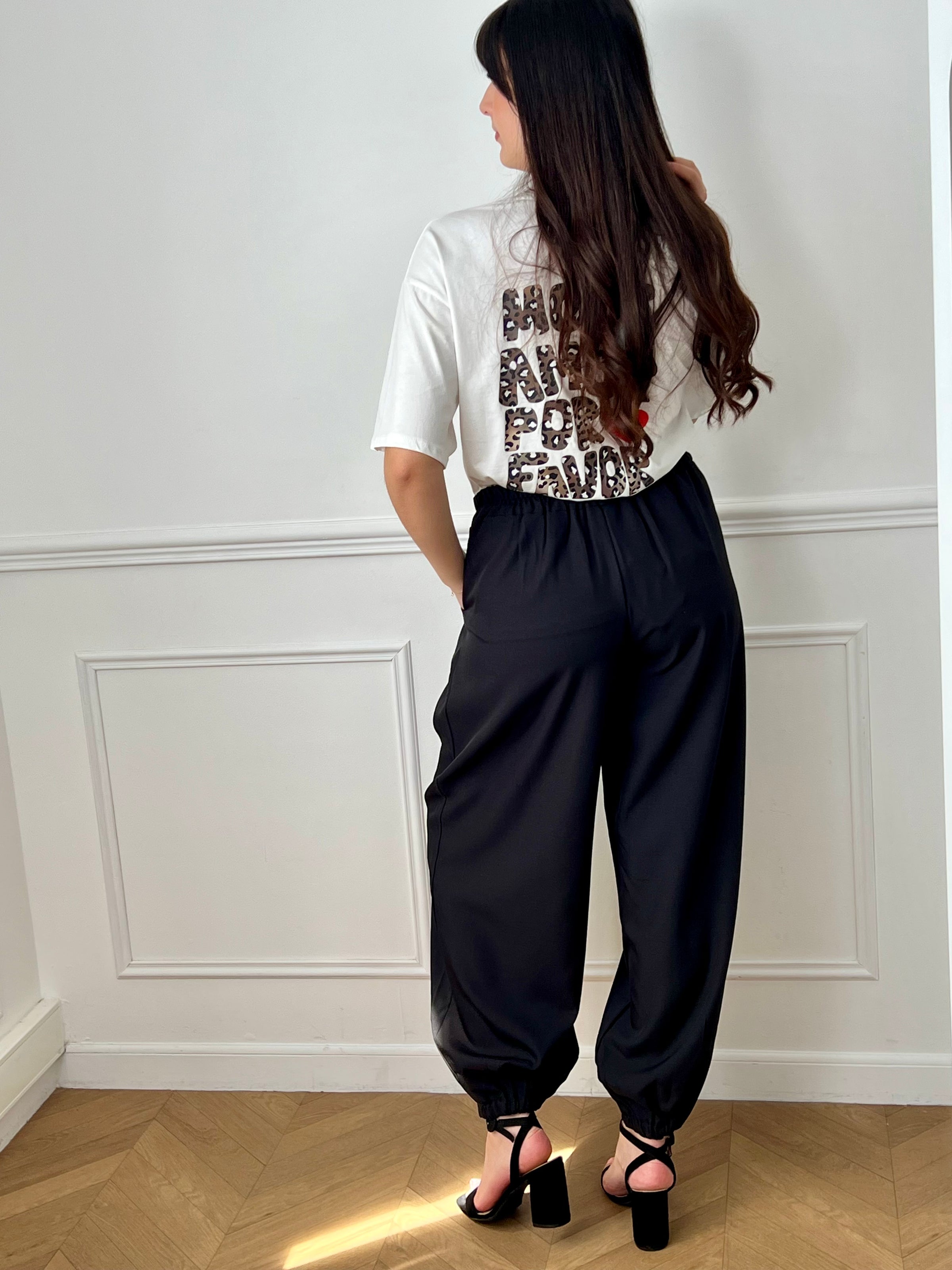 Pantalon noir femme à coupe ballon, idéal pour un look moderne et confortable. Doté de plis sur le devant, d’une taille élastique et de chevilles resserrées, il offre une silhouette tendance. Ses deux poches latérales, sa fermeture par zip et bouton ainsi que ses passants pour ceinture allient praticité et style. Facile à associer, ce pantalon noir est un incontournable du dressing féminin.