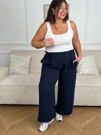 Le pantalon fluide bleu marine Alanis est un incontournable pour votre garde-robe. Avec une taille haute confortable et élastique au dos, ce pantalon large vous assure un ajustement parfait. La ceinture amovible ajoute une touche de peps à votre tenue.