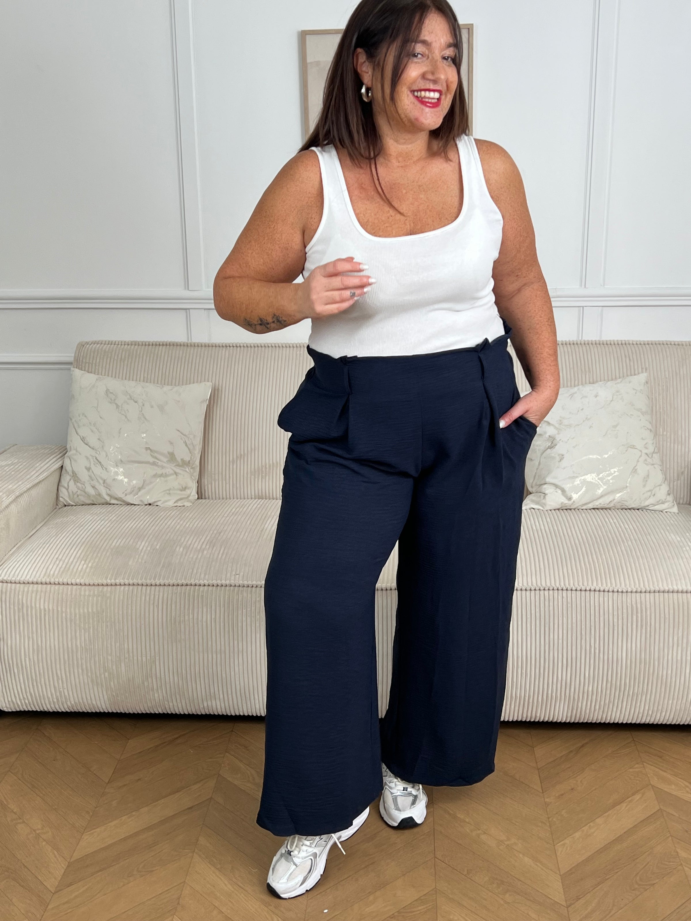 Le pantalon fluide bleu marine Alanis est un incontournable pour votre garde-robe. Avec une taille haute confortable et élastique au dos, ce pantalon large vous assure un ajustement parfait. La ceinture amovible ajoute une touche de peps à votre tenue.