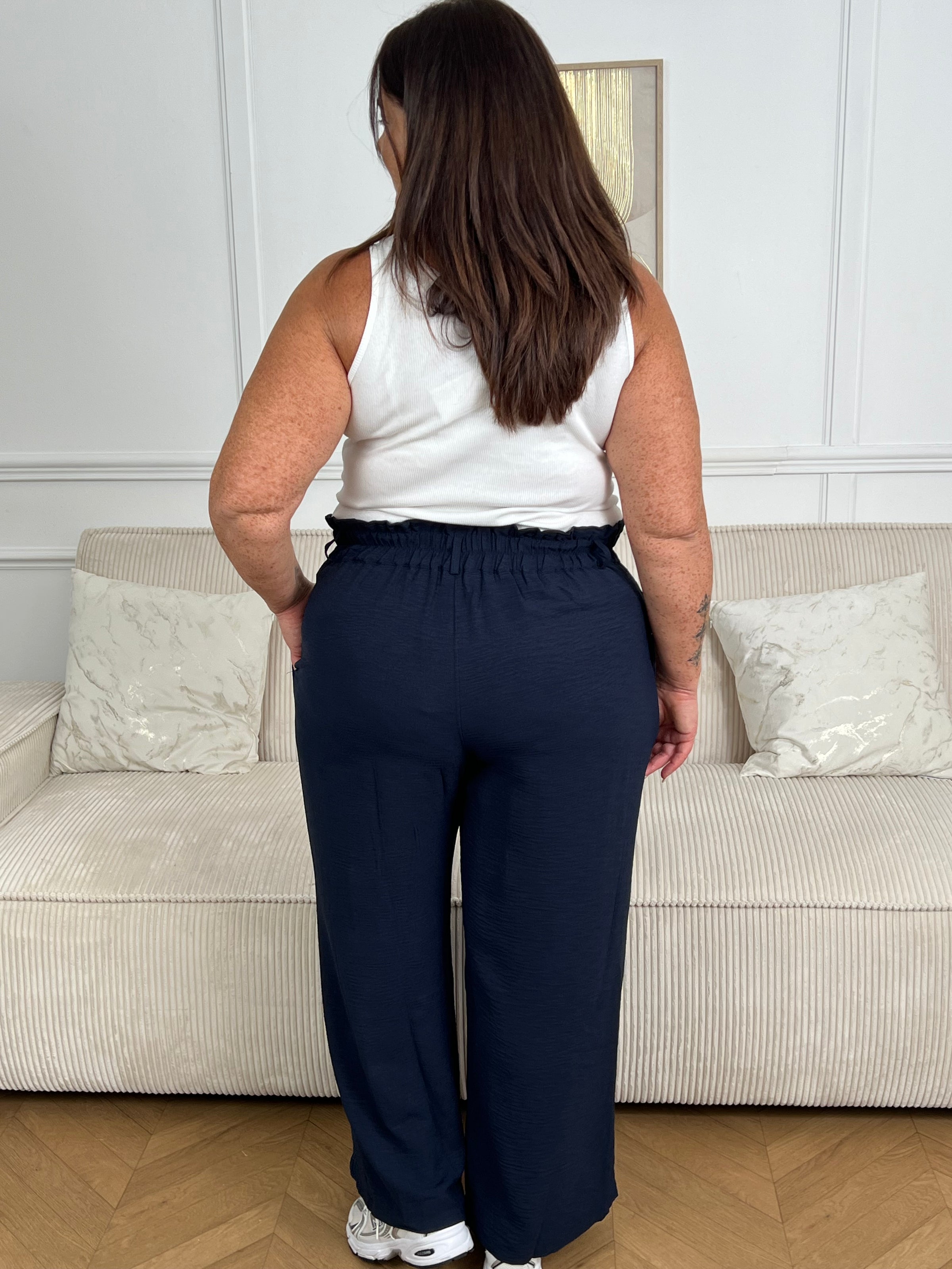Le pantalon fluide bleu marine Alanis est un incontournable pour votre garde-robe. Avec une taille haute confortable et élastique au dos, ce pantalon large vous assure un ajustement parfait. La ceinture amovible ajoute une touche de peps à votre tenue.