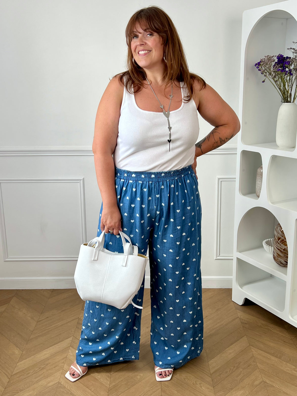 Craquez pour ce pantalon à motifs grande taille femme, à la coupe ample et confortable. Sa taille élastiquée assure un ajustement parfait, tandis que ses deux poches latérales apportent une touche pratique. Avec ses jolis motifs cœurs écrus sur fond bleu, il est idéal pour un look tendance et décontracté.