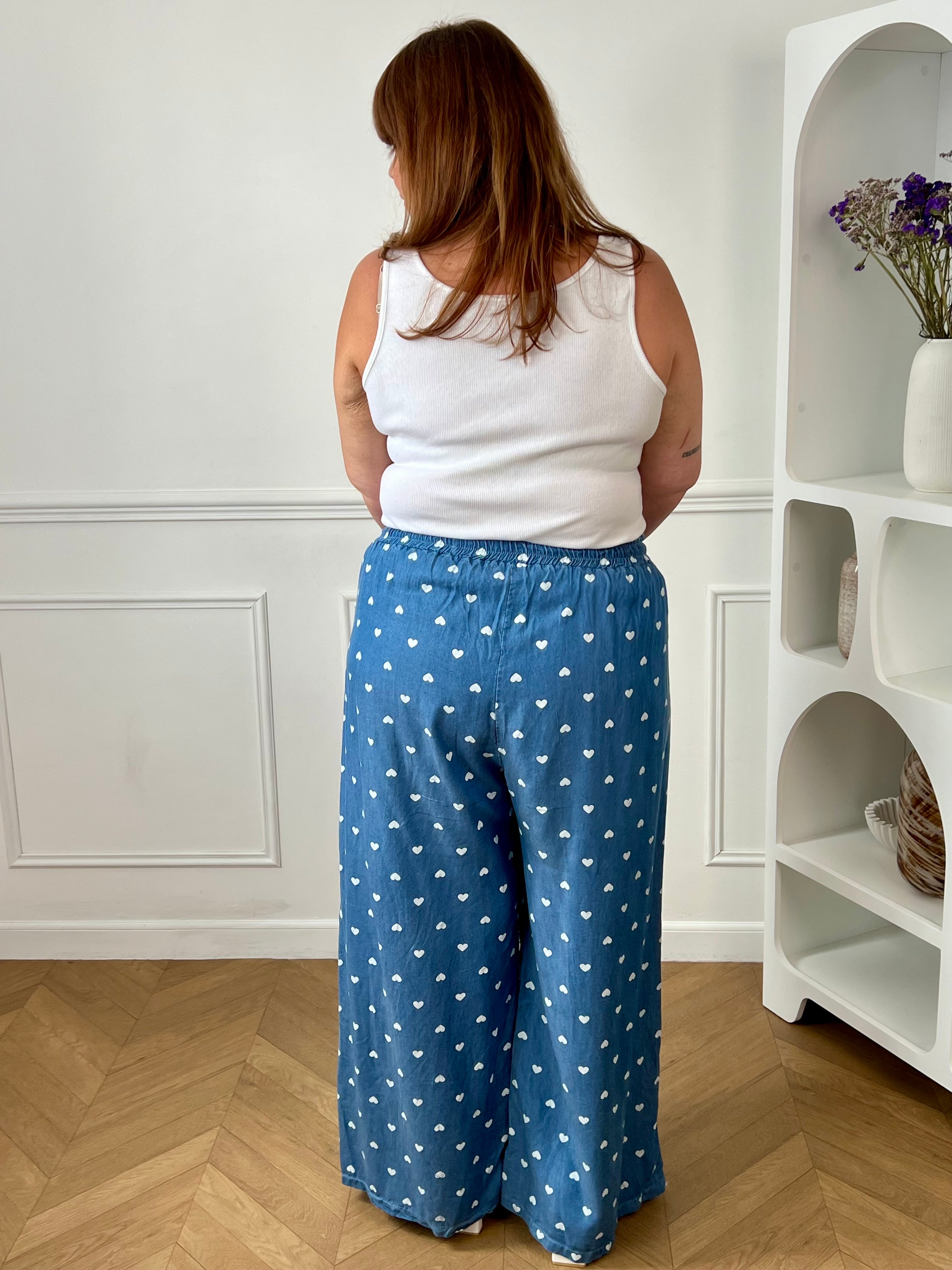 Craquez pour ce pantalon à motifs grande taille femme, à la coupe ample et confortable. Sa taille élastiquée assure un ajustement parfait, tandis que ses deux poches latérales apportent une touche pratique. Avec ses jolis motifs cœurs écrus sur fond bleu, il est idéal pour un look tendance et décontracté.