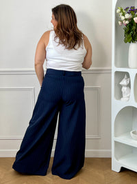 Élégant et intemporel, ce pantalon ample bleu marine à rayures séduit par sa coupe fluide et sa ceinture assortie. Une pièce chic et polyvalente, parfaite pour composer des looks raffinés au quotidien.