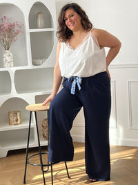 Découvrez le confort ultime avec ce pantalon fluide grande taille Paola. Confectionné dans une matière douce et aérienne, il épouse vos formes sans contrainte grâce à son coupe ample et son élastique discret au dos. Les poches latérales avant offrent praticité et style, tandis que la ceinture amovible à motifs vous permet de personnaliser votre look selon vos envies.