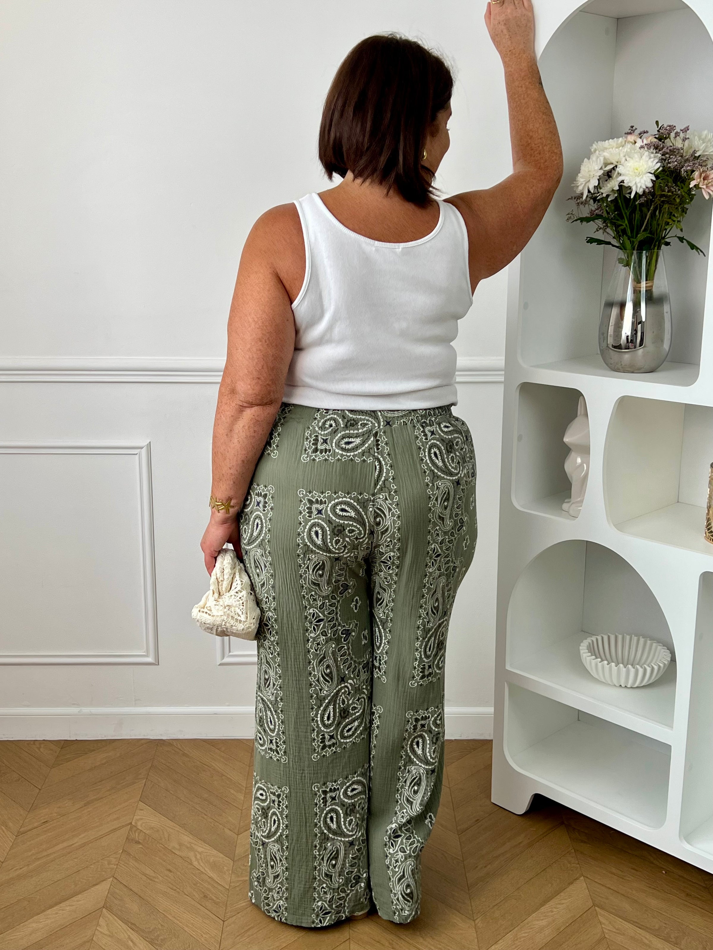 Pantalon kaki en gaze de coton grande taille femme, idéal pour un look confortable et tendance. Doté d’une taille élastique avec cordons factices et de deux poches latérales à l’avant, il offre une coupe ample agréable à porter au quotidien. Ses motifs bleus, noirs et écrus apportent une touche originale et moderne. Léger et fluide, ce pantalon kaki est parfait pour une tenue décontractée et stylée.