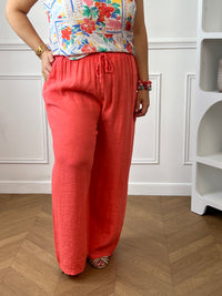 Apportez une touche de fraîcheur à votre dressing avec ce pantalon en lin grande taille femme. Sa taille élastiquée assure un confort optimal au quotidien, tandis que les liens factices ajoutent une finition élégante et décontractée. Doté de deux poches latérales pratiques à l’avant, ce modèle légèrement transparent séduit par sa matière légère et respirante. Sa couleur corail lumineuse en fait une pièce idéale pour composer des looks estivaux à la fois confortables et tendance.
