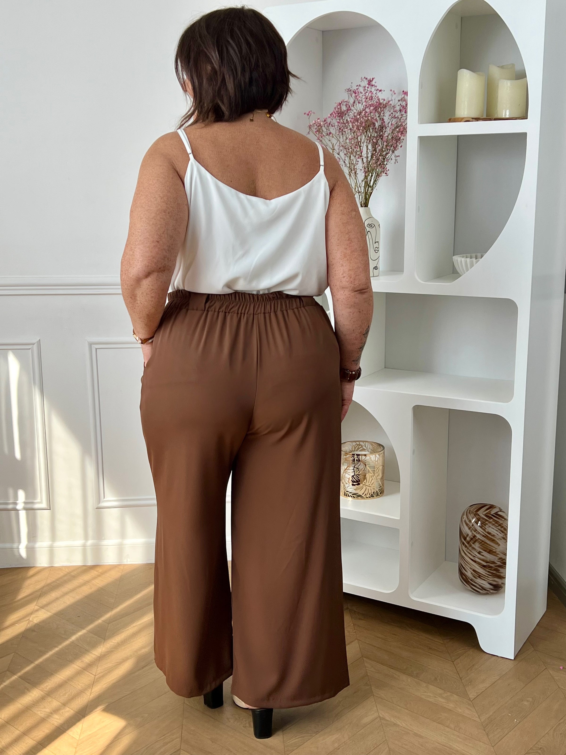 Ce pantalon marron coupe droite grande taille pour femme est l'élégance incarnée. Avec sa matière fluide, il offre un confort optimal et sa coupe droite flatteuse convient à toutes les morphologies. L'élastique au dos garantit un ajustement parfait et les passants pour ceinture sont pratiques. Ajoutez-y un style sophistiqué avec ses deux poches latérales.