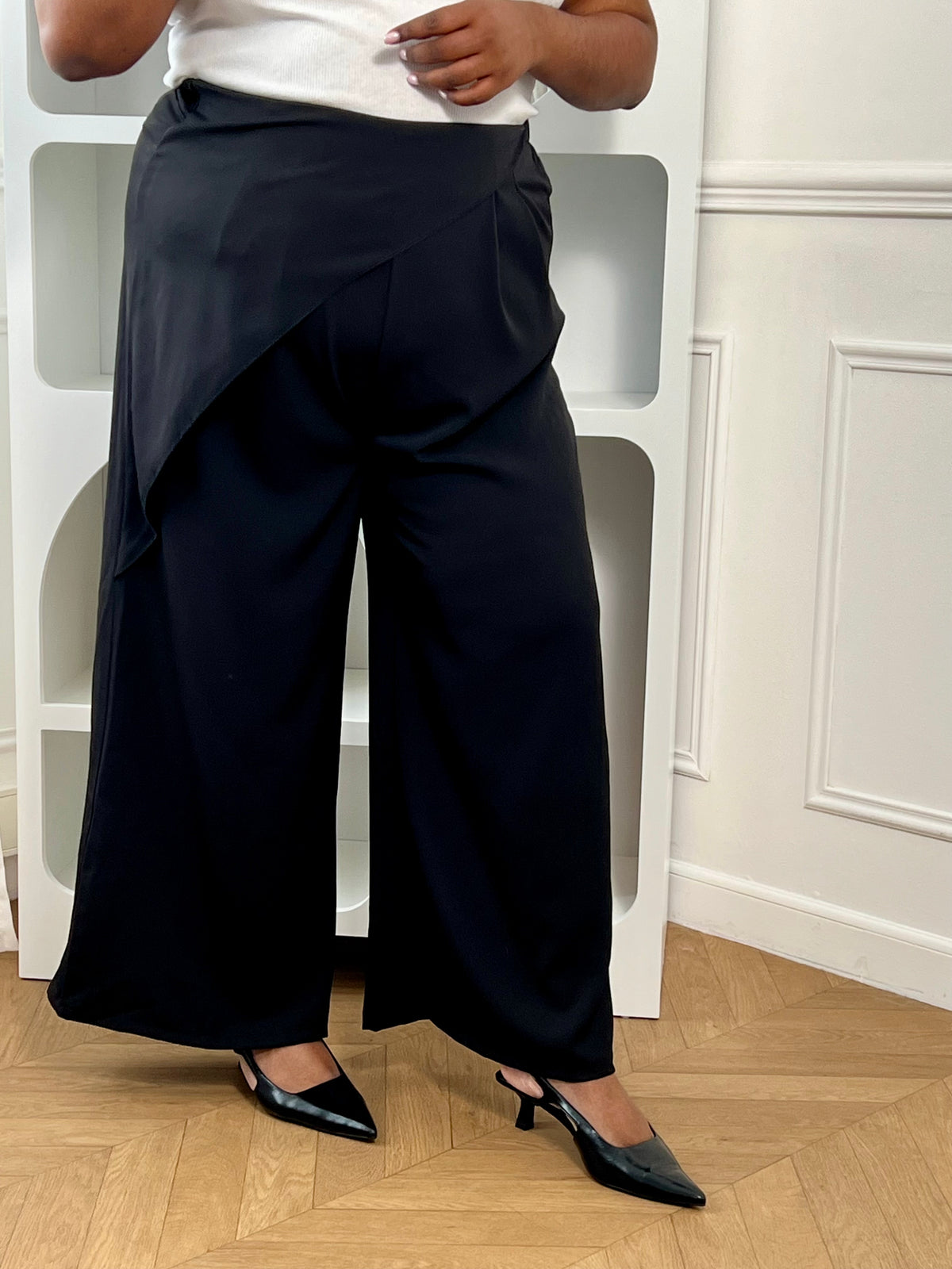 Pantalon coupe portefeuille grande taille femme, élégant et fluide. Son tissu asymétrique sur le devant apporte une touche originale, tandis que son élastique au dos assure un confort optimal. Doté de passants pour ceinture et de deux poches latérales, il est idéal pour un look à la fois chic et décontracté.