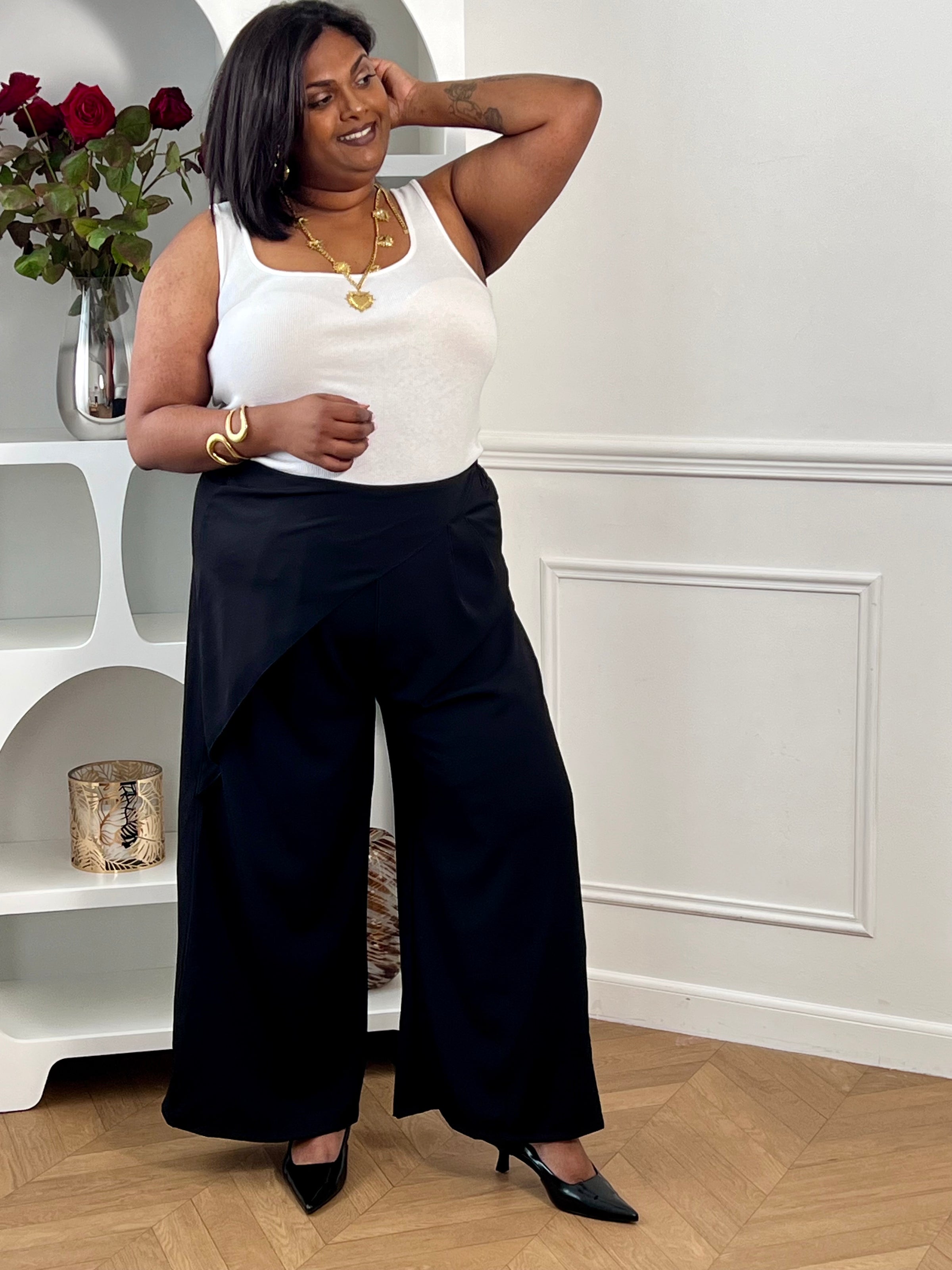 Pantalon coupe portefeuille grande taille femme, élégant et fluide. Son tissu asymétrique sur le devant apporte une touche originale, tandis que son élastique au dos assure un confort optimal. Doté de passants pour ceinture et de deux poches latérales, il est idéal pour un look à la fois chic et décontracté.