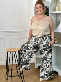 Pantalon à motifs grande taille femme, fluide et confortable, idéal pour un look tendance au quotidien. Doté d’une taille élastique, de poches latérales et de passants avec ceinture amovible, il s’adapte parfaitement à la silhouette. Ses motifs fleuris aux nuances noir, gris, taupe et écru apportent une touche élégante et féminine. Ce pantalon fluide est parfait pour une tenue chic et décontractée.
