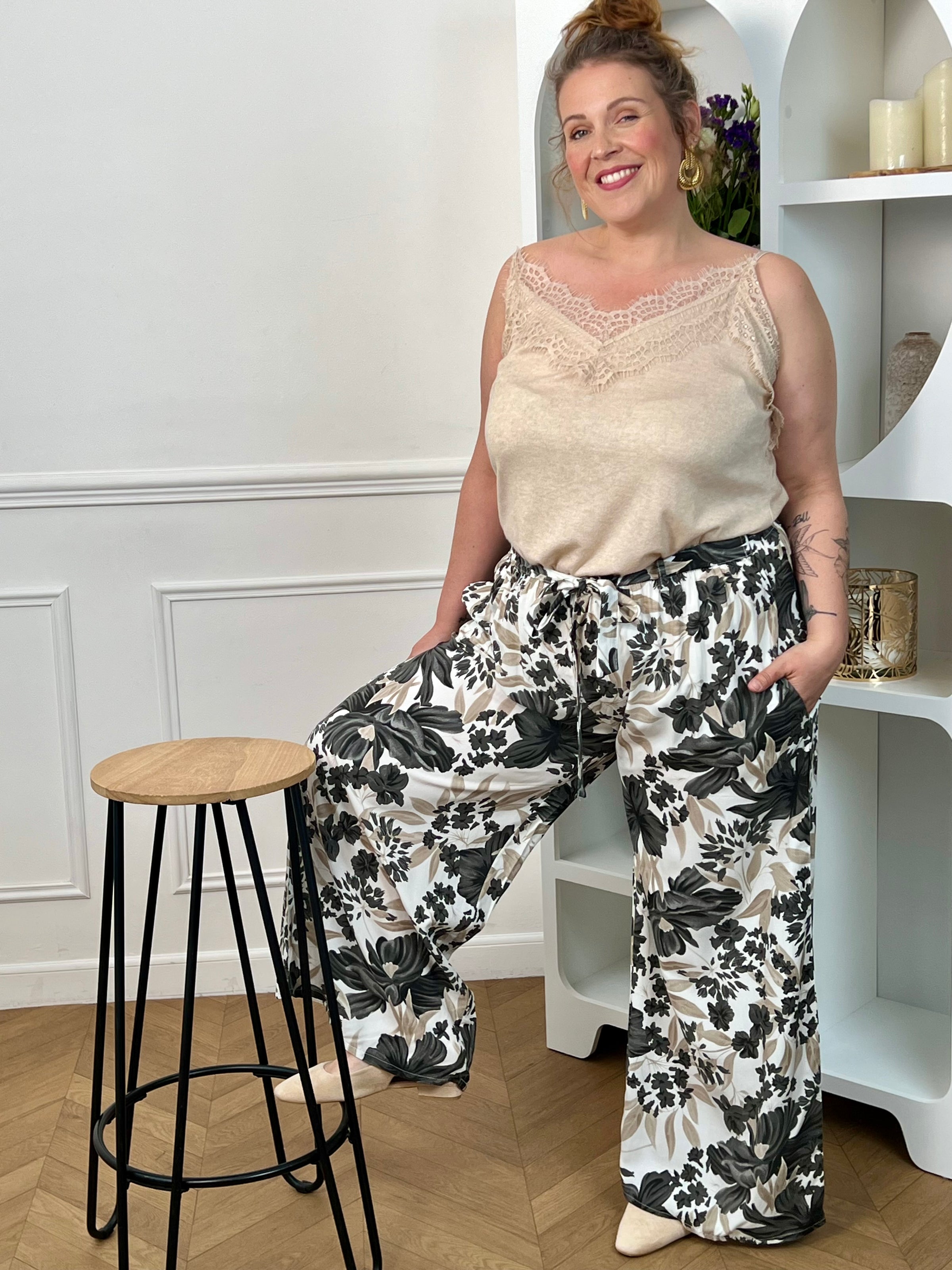 Pantalon à motifs grande taille femme, fluide et confortable, idéal pour un look tendance au quotidien. Doté d’une taille élastique, de poches latérales et de passants avec ceinture amovible, il s’adapte parfaitement à la silhouette. Ses motifs fleuris aux nuances noir, gris, taupe et écru apportent une touche élégante et féminine. Ce pantalon fluide est parfait pour une tenue chic et décontractée.
