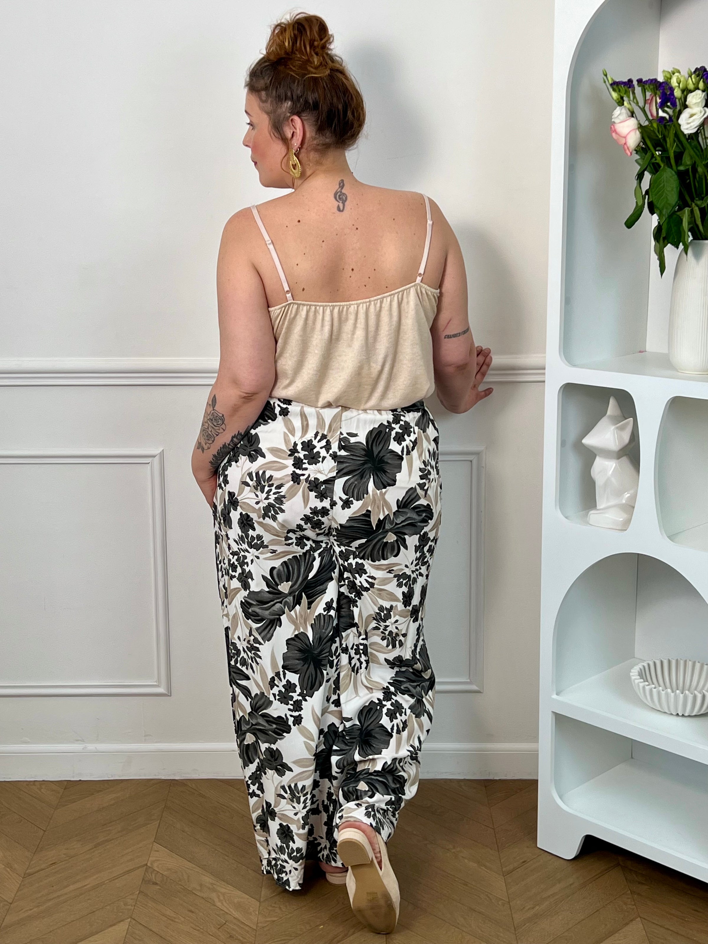 Pantalon à motifs grande taille femme, fluide et confortable, idéal pour un look tendance au quotidien. Doté d’une taille élastique, de poches latérales et de passants avec ceinture amovible, il s’adapte parfaitement à la silhouette. Ses motifs fleuris aux nuances noir, gris, taupe et écru apportent une touche élégante et féminine. Ce pantalon fluide est parfait pour une tenue chic et décontractée.