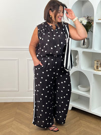 Adoptez un style à la fois tendance et confortable avec ce pantalon large noir grande taille à motifs pois écrus. Sa taille élastiquée assure un ajustement parfait, tandis que sa coupe fluide offre une grande liberté de mouvement. Les rayures écrues sur les côtés apportent une touche moderne et élancent la silhouette. Doté de poches latérales pratiques et confectionné dans une matière légèrement transparente, ce pantalon noir et écru est idéal pour composer des looks élégants et décontractés.