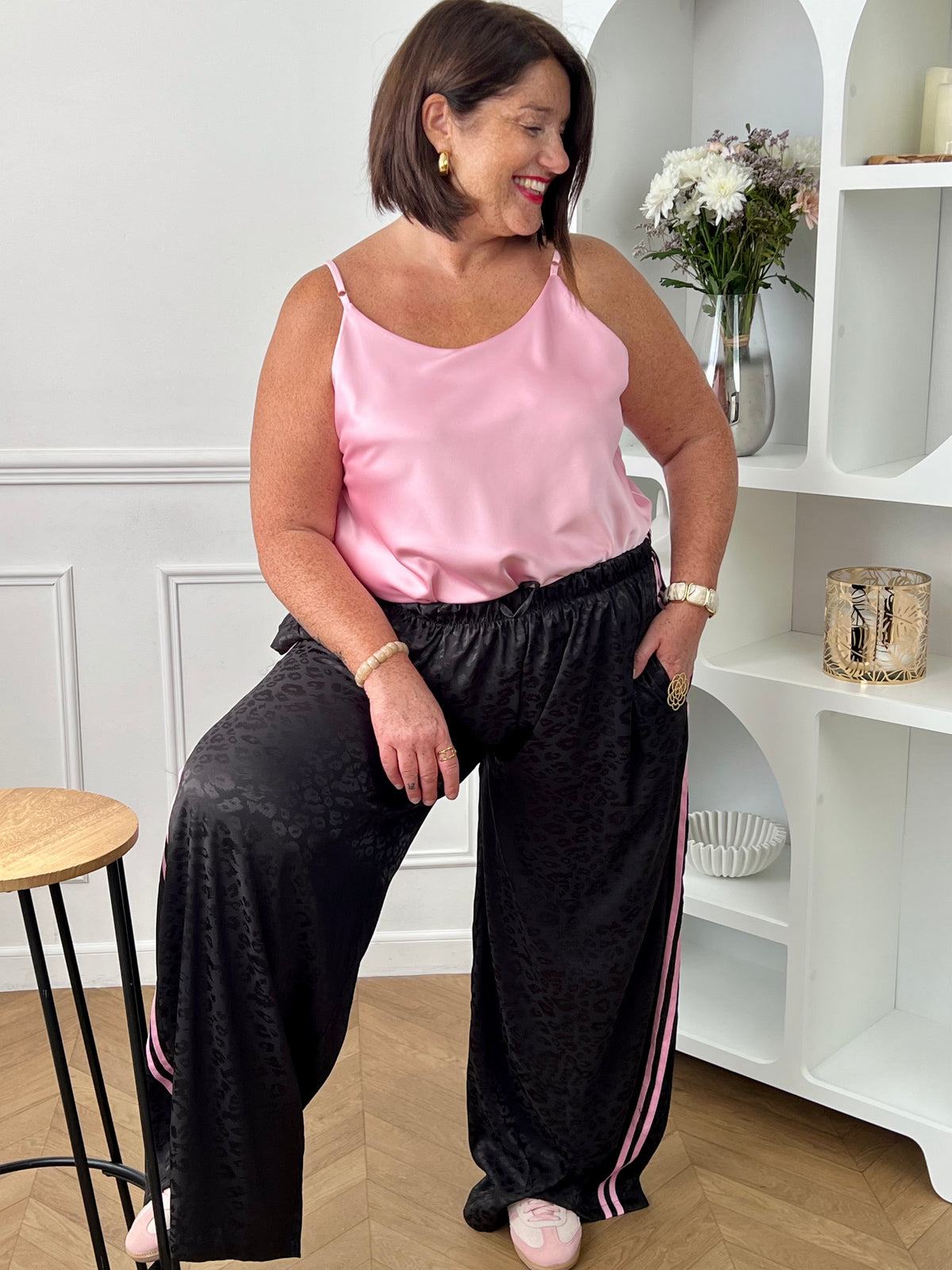 Pantalon large noir femme grande taille, au style décontracté et tendance. Sa coupe longue effet jogging assure un confort optimal, tandis que sa taille élastique avec liens de serrage s'adapte parfaitement à votre silhouette. Agrémenté de motifs panthère, de rayures roses sur les côtés et de poches latérales pratiques, ce pantalon allie originalité et féminité pour un look moderne et confortable.