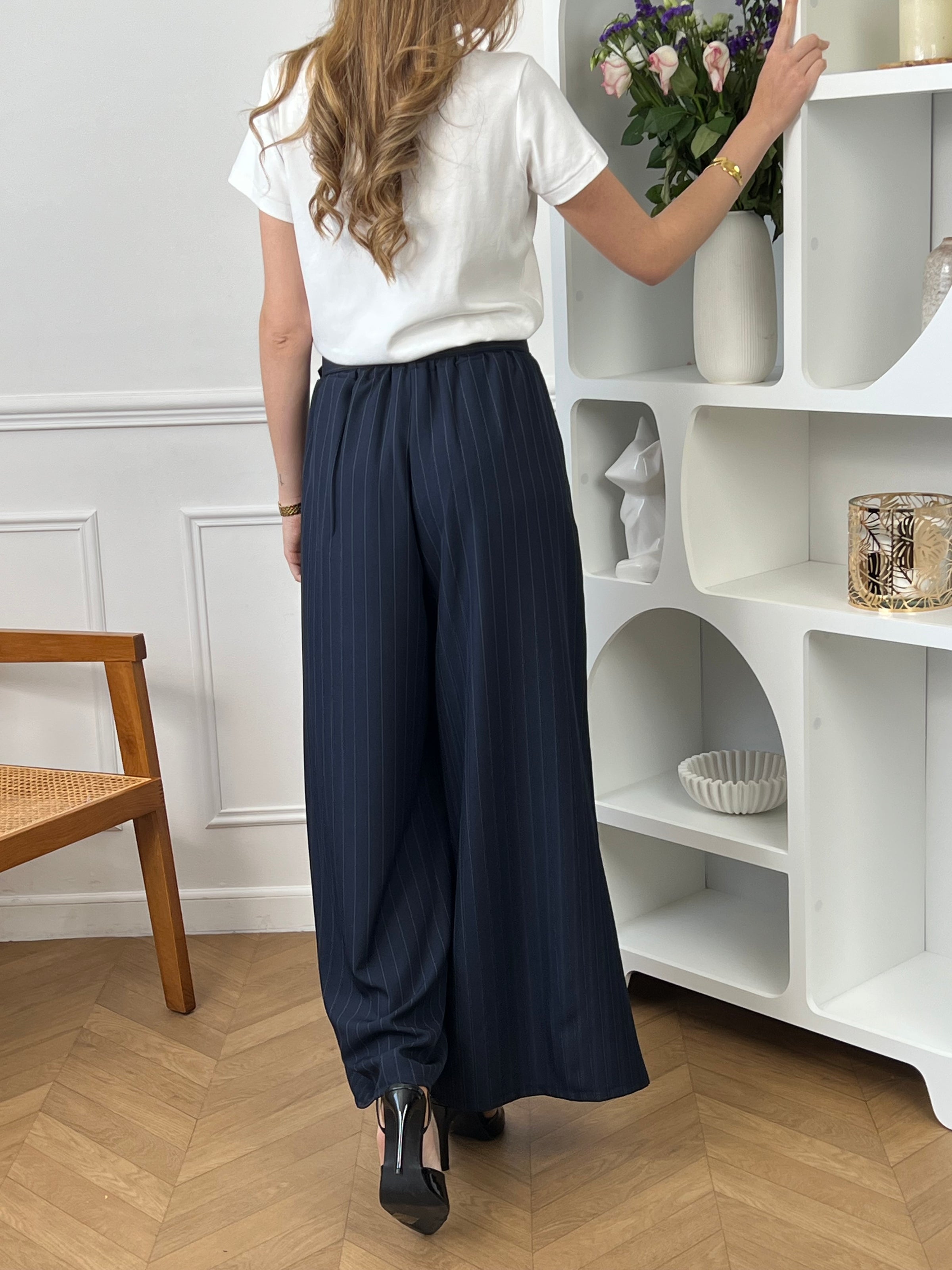 Élégant et intemporel, ce pantalon ample bleu marine à rayures séduit par sa coupe fluide et sa ceinture assortie. Une pièce chic et polyvalente, parfaite pour composer des looks raffinés au quotidien.