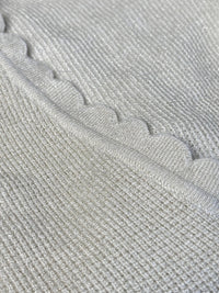 Le pull Celestina combine élégance et sensualité avec son dos nu en V à lien noué et ses manches longues. Orné de fil lurex doré, ce pull beige et doré brille de mille feux. Son col rond festonné ajoute une touche de raffinement pour des occasions spéciales.