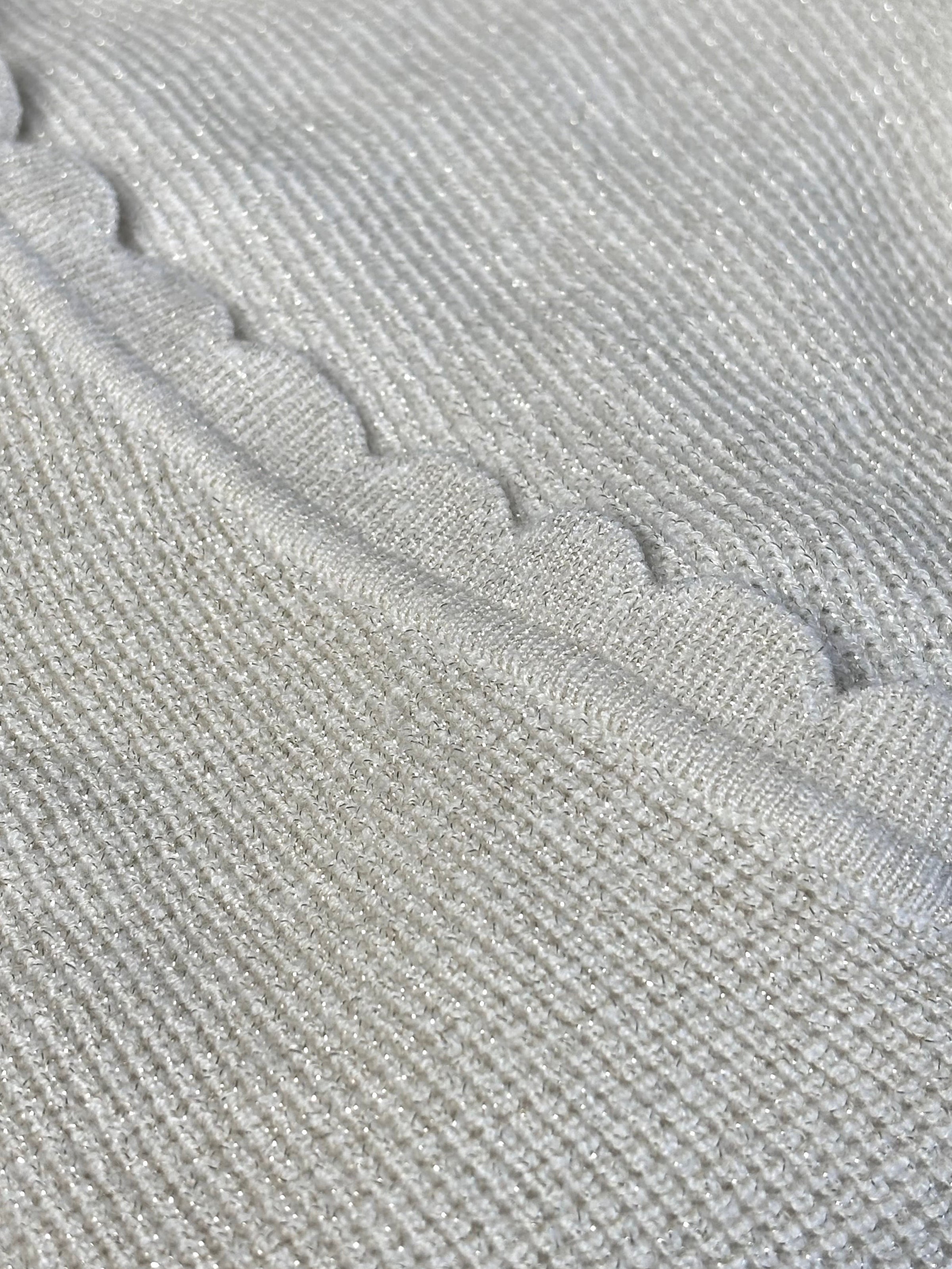 Le pull Celestina combine élégance et sensualité avec son dos nu en V à lien noué et ses manches longues. Orné de fil lurex doré, ce pull beige et doré brille de mille feux. Son col rond festonné ajoute une touche de raffinement pour des occasions spéciales.