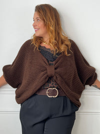 Pull marron Aelina à encolure V et détail noué devant, montrant la maille texturée et les manches larges remontées.