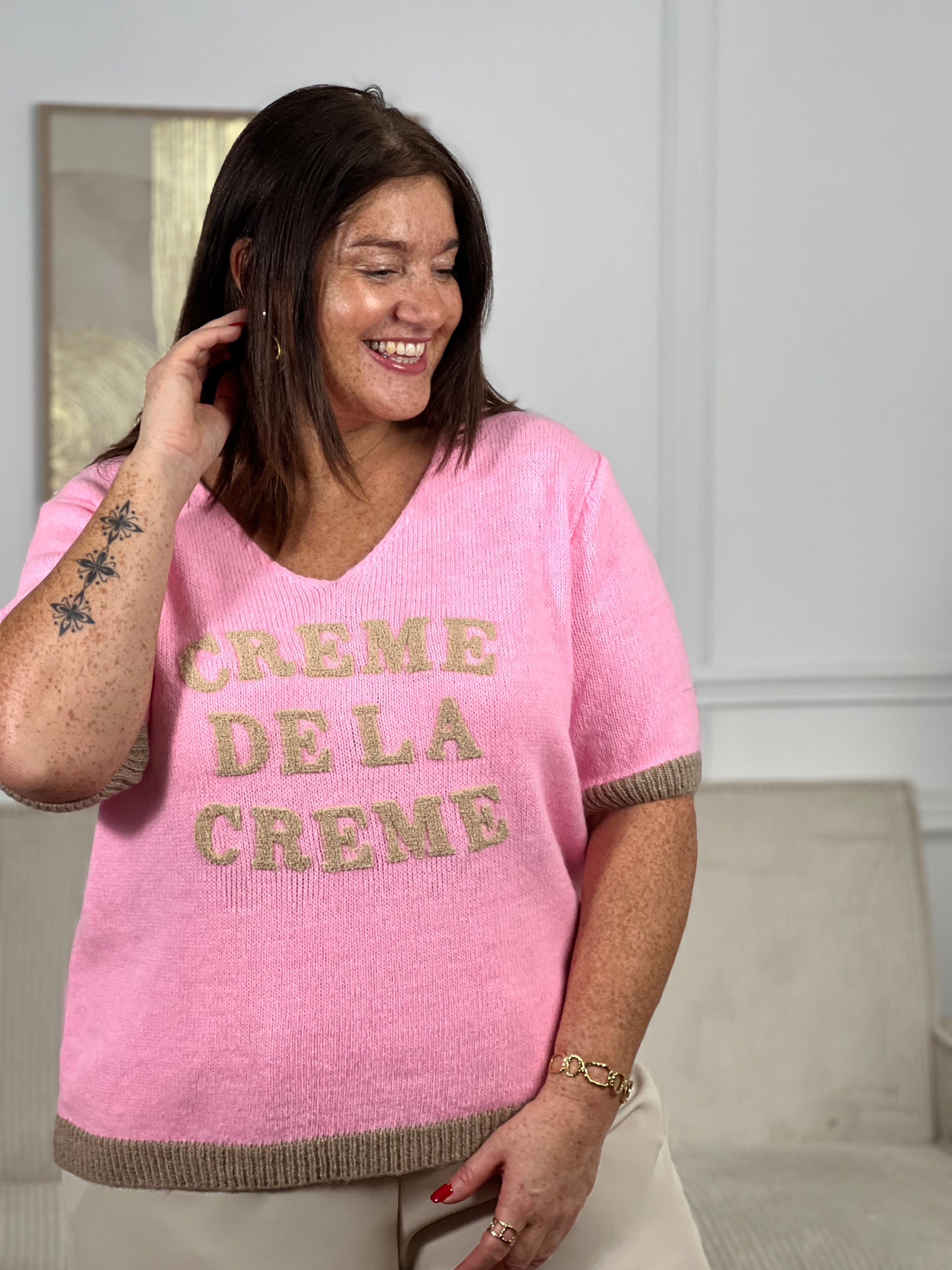 Pull rose grande taille Niya : élégance et confort réunis. Coupe généreuse avec manches courtes et col V flatteuse, parfait pour les silhouettes généreuses. Détail signature : inscription camel en relief "Crème de la crème" qui affirme votre style avec assurance. Bordures taupe sophistiquées pour une finition soignée.