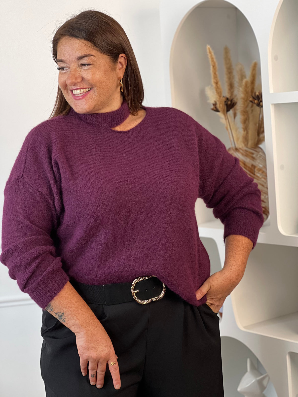 Pull violet grande taille vu de près, montrant son encolure à découpe asymétrique, porté avec un pantalon noir ceinturé – Daisie | Loïcia