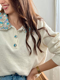 Découvrez le Pull Amelys, une pièce incontournable alliant élégance et confort. Doté d'un col claudine orné de motifs fleuris délicats, ce pull long manches apporte une touche romantique à votre garde-robe. Les boutons à motifs sur le devant ajoutent du caractère et du détail à cette création.