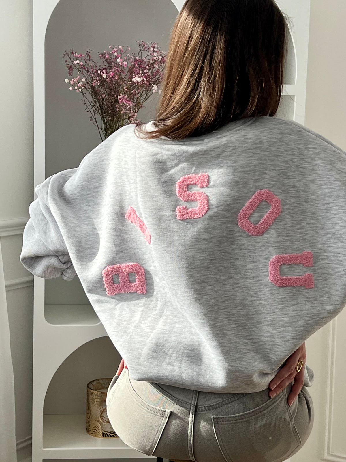Adoptez ce sweat gris femme à la coupe large, confortable et tendance. Doté d’un col rond et de manches longues, il se distingue par son inscription “Bisou” en rose au dos qui apporte une touche originale. Un sweat gris et rose parfait pour un look casual et moderne.