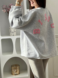 Adoptez ce sweat gris femme à la coupe large, confortable et tendance. Doté d’un col rond et de manches longues, il se distingue par son inscription “Bisou” en rose au dos qui apporte une touche originale. Un sweat gris et rose parfait pour un look casual et moderne.