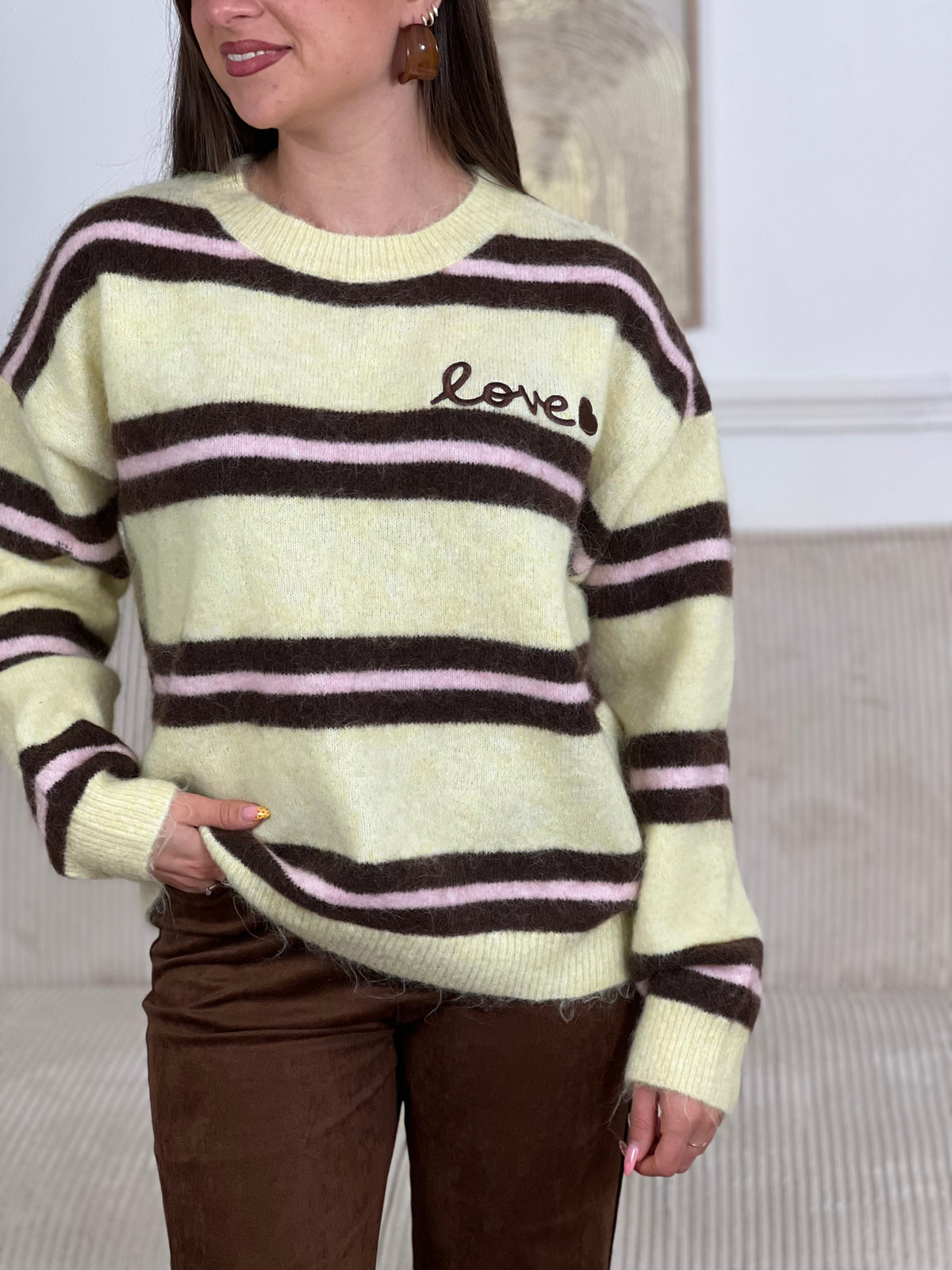 Un incontournable de votre garde-robe automne-hiver. Ce pull femme en laine allie confort et style avec ses manches longues et son col rond épuré. Les rayures horizontales marron et roses créent une harmonie visuelle intemporelle, tandis que l'inscription "Love" ornée d'un cœur marron ajoute une touche de tendresse au devant.