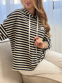 Sweat à capuche en coton à rayures style marinière, idéal pour un look décontracté et tendance. Avec ses manches longues et ses poignets élastiqués, il offre confort et maintien. Sa capuche avec lien de serrage écru et ses rayures horizontales écrues et bleues apportent une touche intemporelle. Agrémenté d’un motif smiley et de l’inscription "Here", ce sweat aux tons bleu marine, beige et écru est parfait pour un style casual moderne.