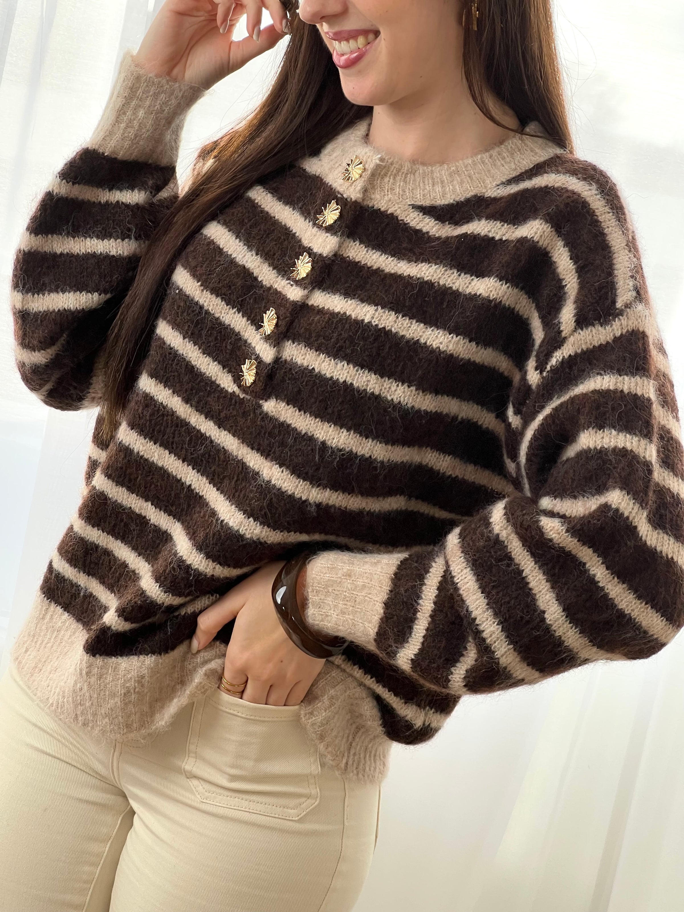 Le pull Maelion allie style et confort avec ses rayures horizontales marron et beige. Manches longues, col rond et boutons dorés sur le devant pour une allure sophistiquée. Une pièce polyvalente qui s'adapte à tous vos looks.