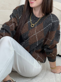 Pull femme Solea aux motifs losanges géométriques. Manches longues et col rond pour un style intemporel. Teintes harmonieuses de marron, écru et gris foncé qui s'associent facilement à vos tenues du quotidien.