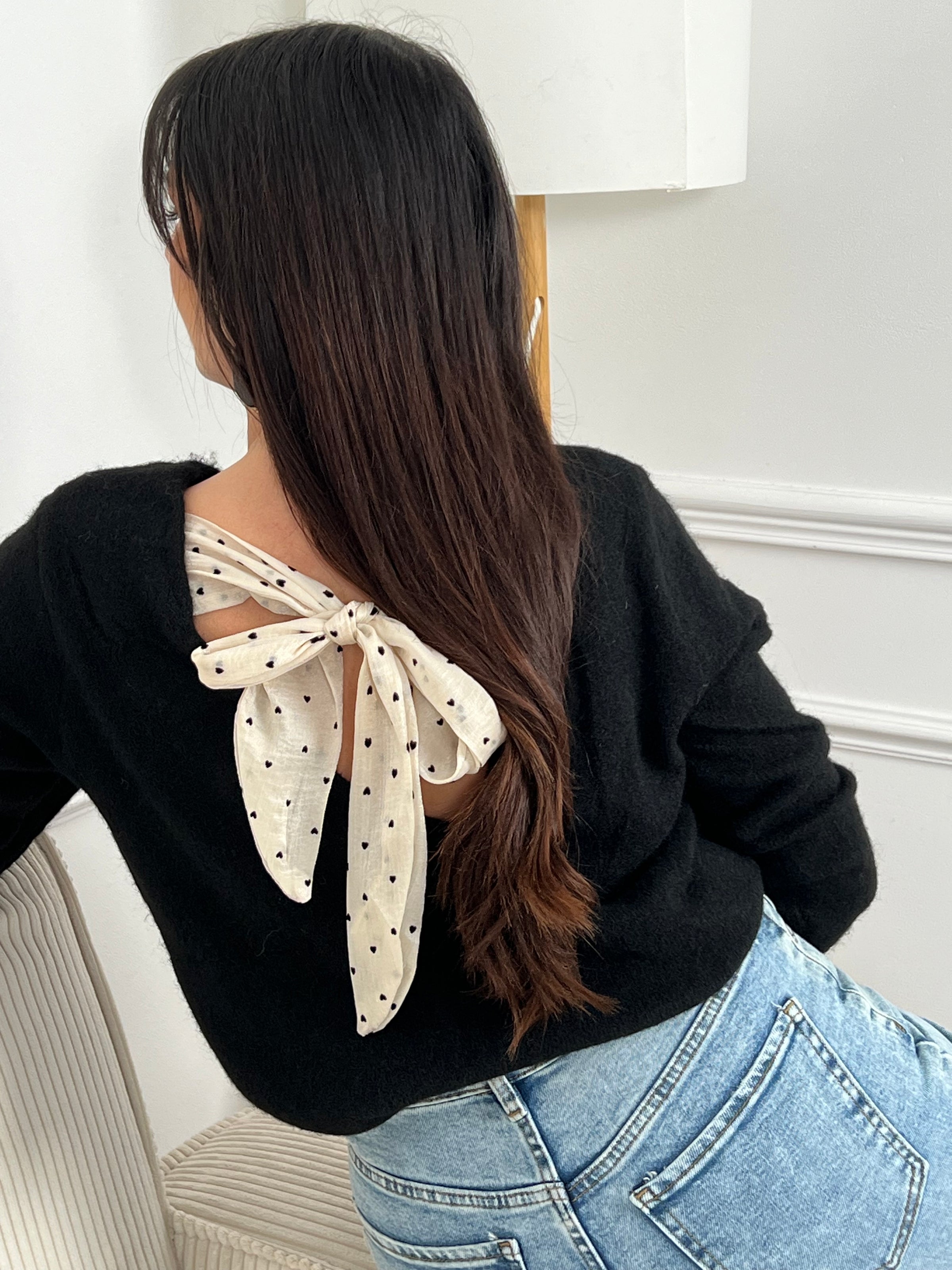 Indispensable et féminin, ce pull noir au dos nu en V séduit par son lien beige à nouer orné de petits cœurs noirs. Une pièce raffinée et moderne, facile à porter et parfaite pour apporter une touche de charme à vos looks du quotidien.