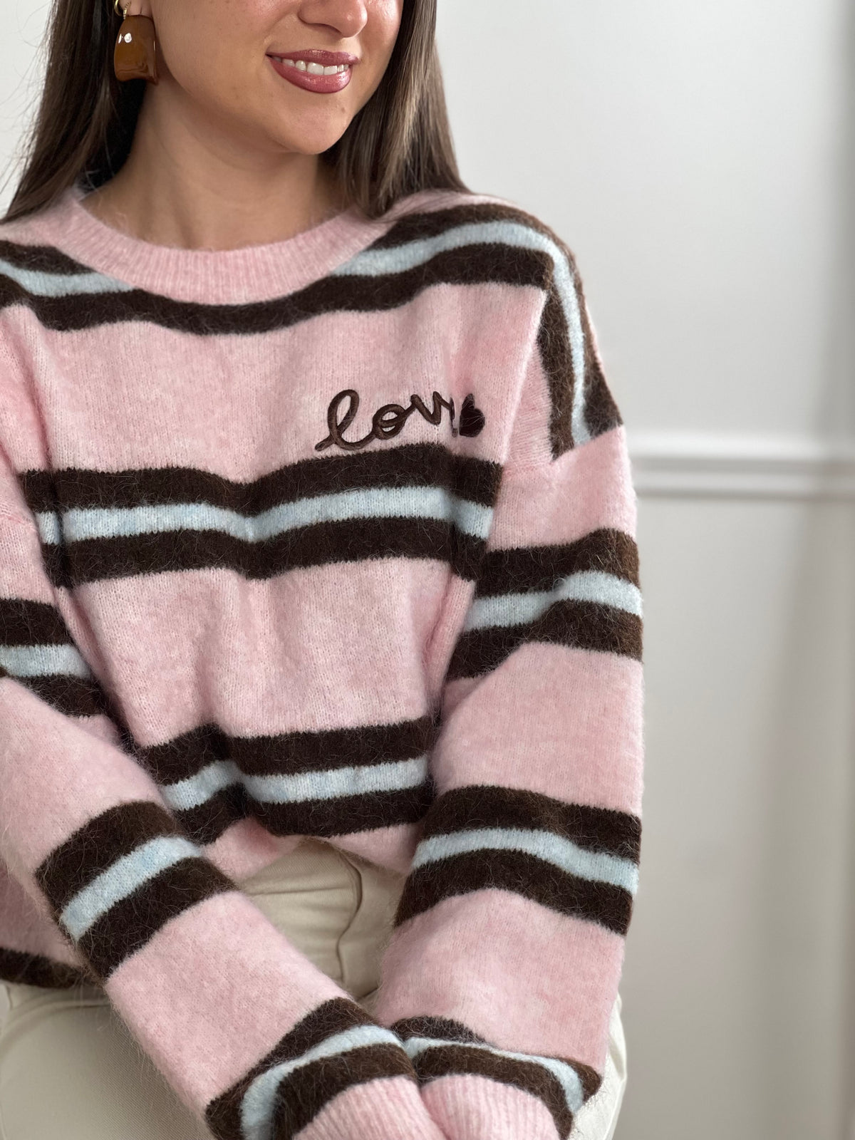 Un incontournable de votre garde-robe automne-hiver. Ce pull femme en laine allie confort et style avec ses manches longues et son col rond épuré. Les rayures horizontales marron et bleues créent une harmonie visuelle intemporelle, tandis que l'inscription "Love" ornée d'un cœur marron ajoute une touche de tendresse au devant.