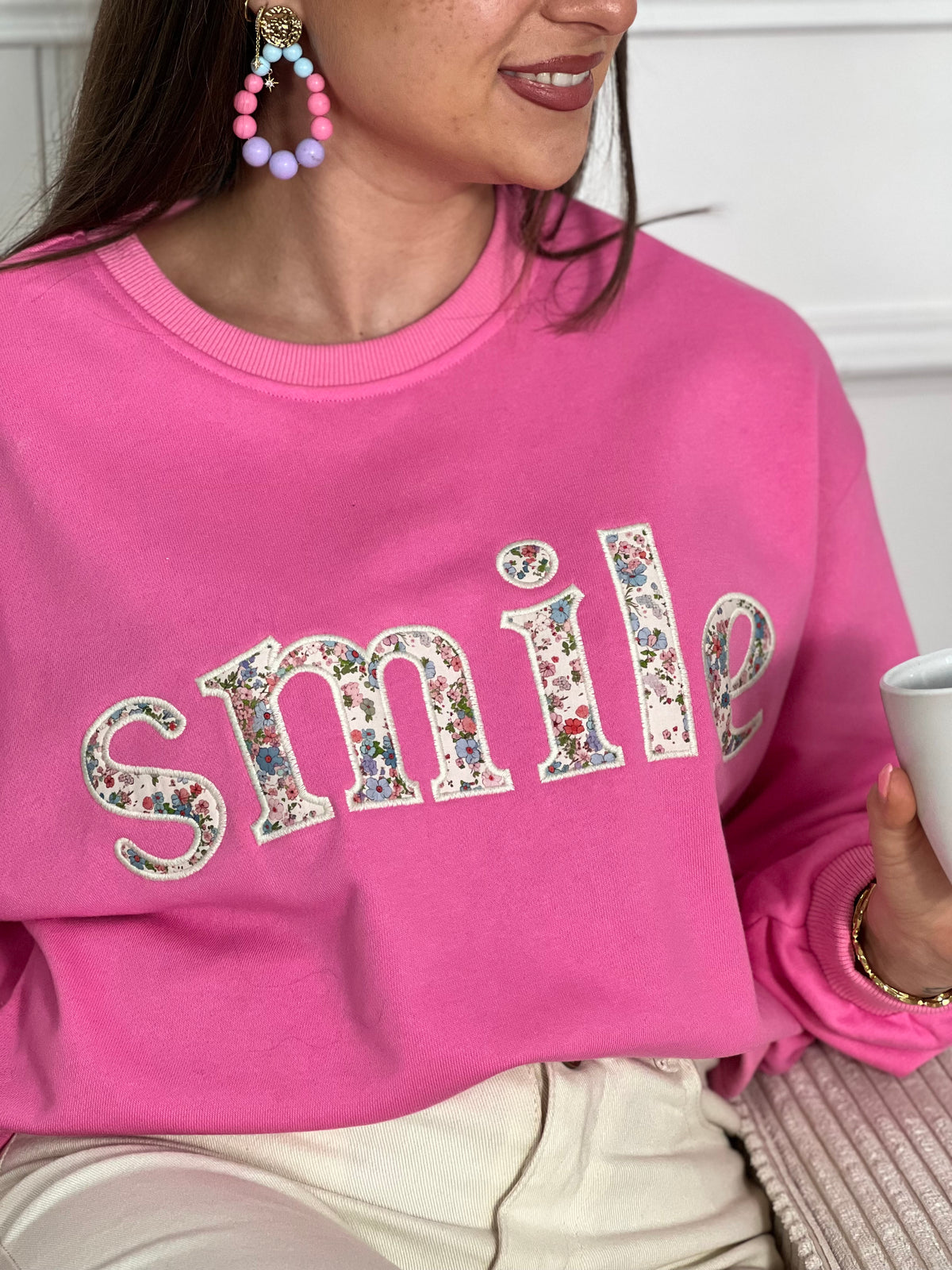 Sweat rose confortable aux manches longues, parfait pour les journées fraîches. Son col rond classique offre une allure intemporelle, tandis que l'inscription "SMILE" brodée avec des motifs fleuris délicats ajoute une touche de personnalité et de douceur. Un basique polyvalent à porter seul ou en superposition, idéal pour exprimer votre style avec bienveillance.