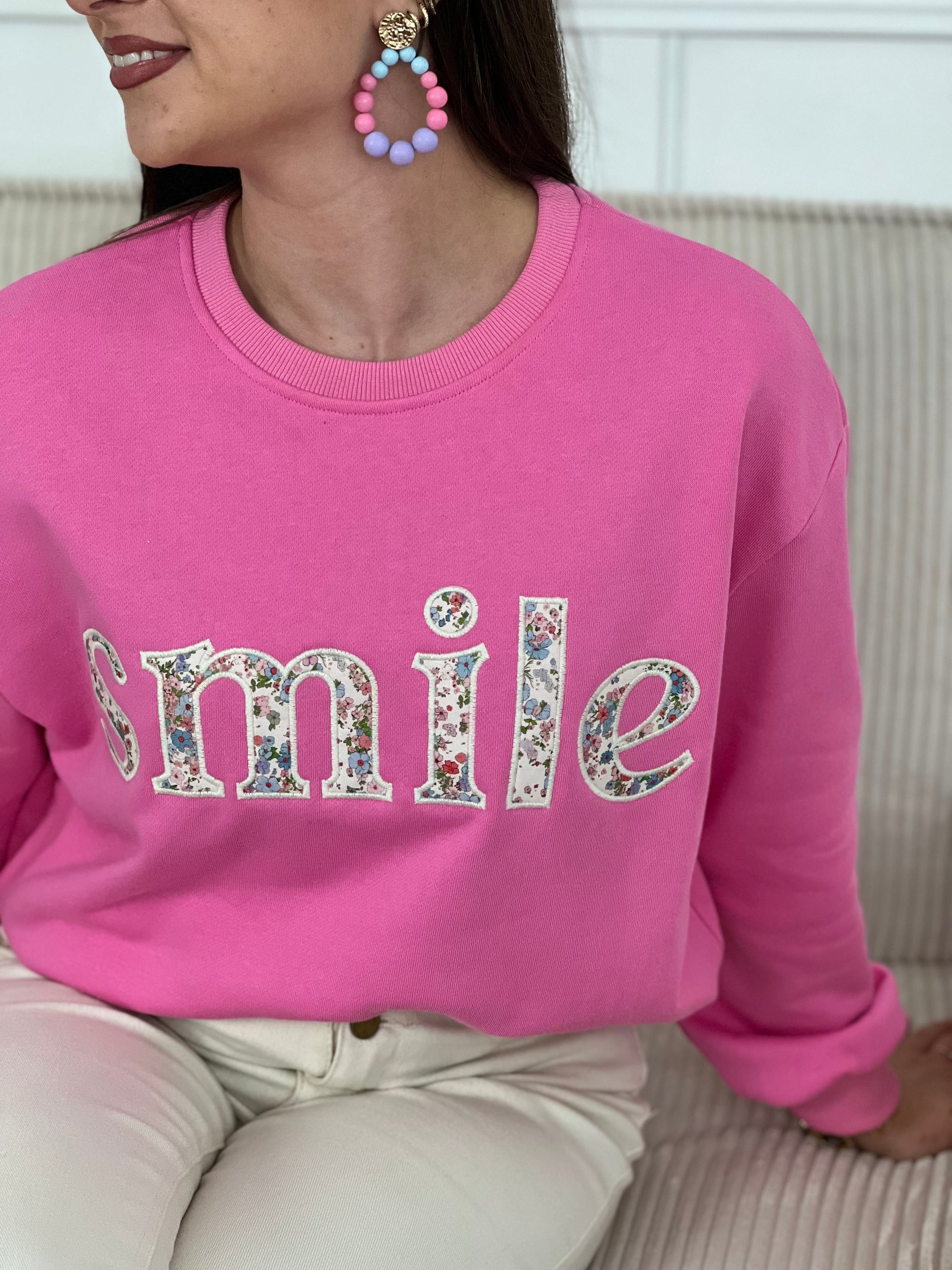 Sweat rose confortable aux manches longues, parfait pour les journées fraîches. Son col rond classique offre une allure intemporelle, tandis que l'inscription "SMILE" brodée avec des motifs fleuris délicats ajoute une touche de personnalité et de douceur. Un basique polyvalent à porter seul ou en superposition, idéal pour exprimer votre style avec bienveillance.