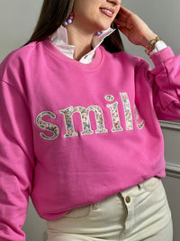 Sweat rose confortable aux manches longues, parfait pour les journées fraîches. Son col rond classique offre une allure intemporelle, tandis que l'inscription "SMILE" brodée avec des motifs fleuris délicats ajoute une touche de personnalité et de douceur. Un basique polyvalent à porter seul ou en superposition, idéal pour exprimer votre style avec bienveillance.